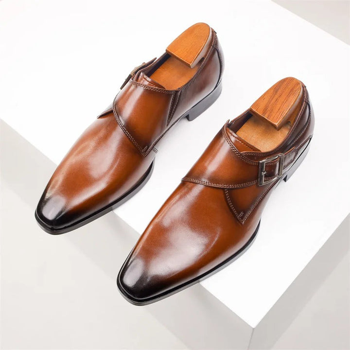 Pair of tan leather monk strap shoes viewed from above on plinth