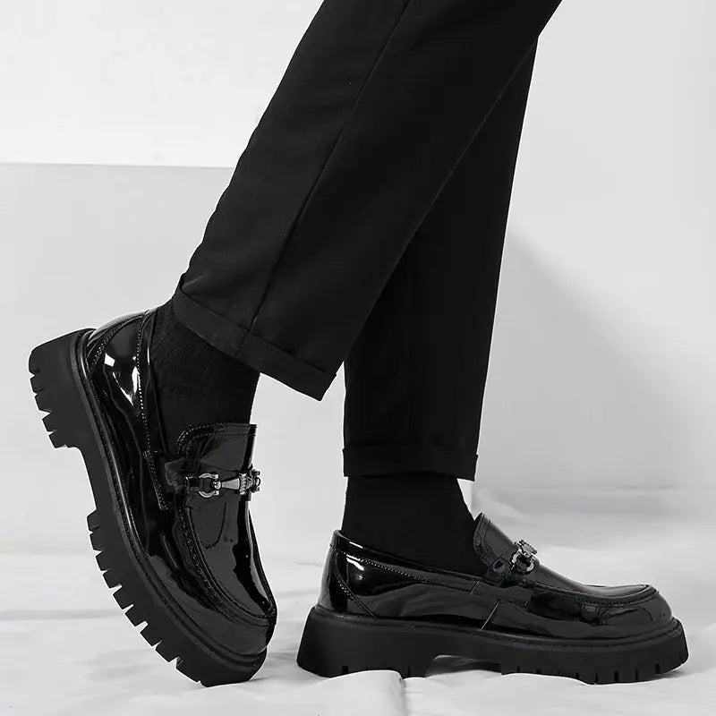 Black patent leather loafers worn with cuffed trousers, chunky sole in profile