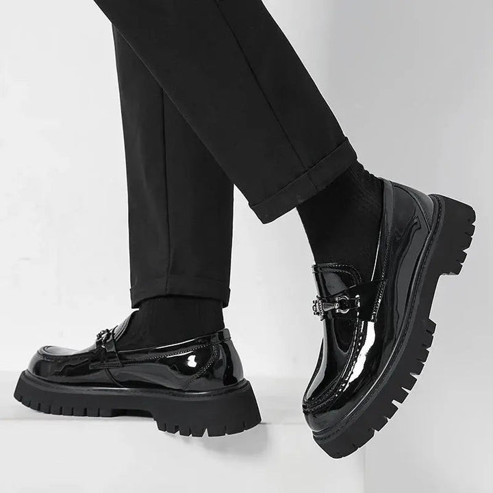 Black patent leather loafer shown mid-step, revealing deep tread platform sole
