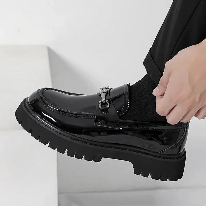 Hand adjusting black patent loafer with buckle strap over ankle sock