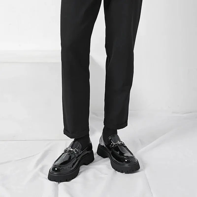 Model standing in black patent leather loafers with slim black trousers