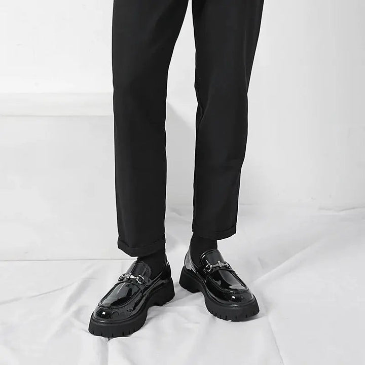 Model standing in black patent leather loafers with slim black trousers
