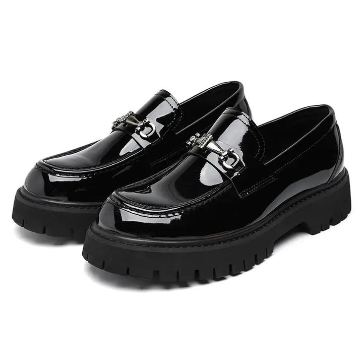 Pair of glossy black patent leather loafers with silver buckle, platform sole visible