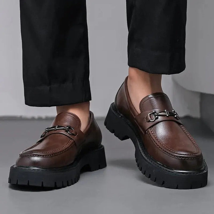 Brown leather slip-on loafers styled with black trousers, chunky ridged sole shown