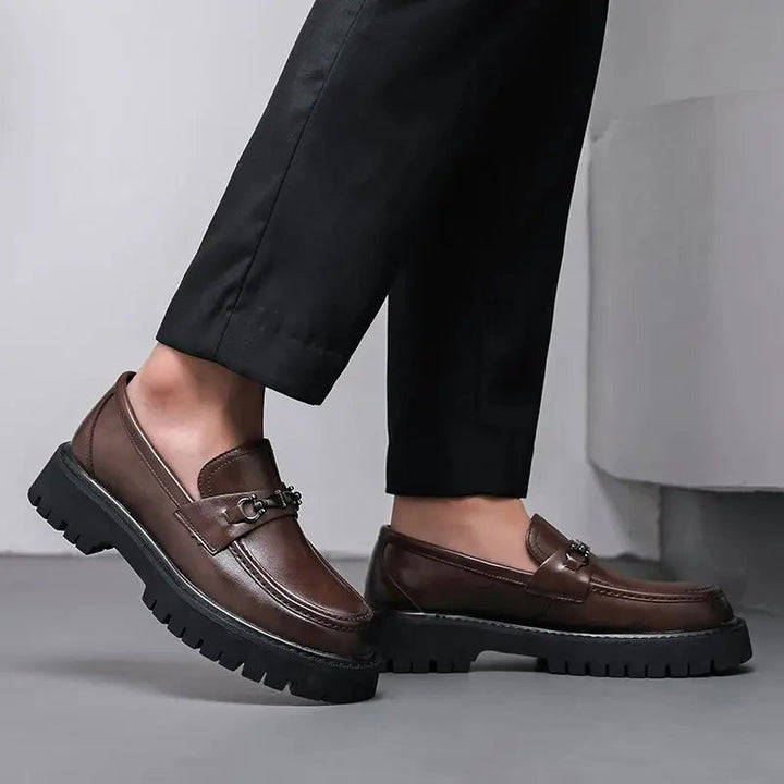 Brown leather loafers paired with black trousers, showing thick lugged outsole