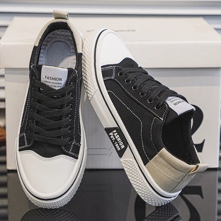 Black canvas lace-up sneakers with white toe caps and contrast stitching detail