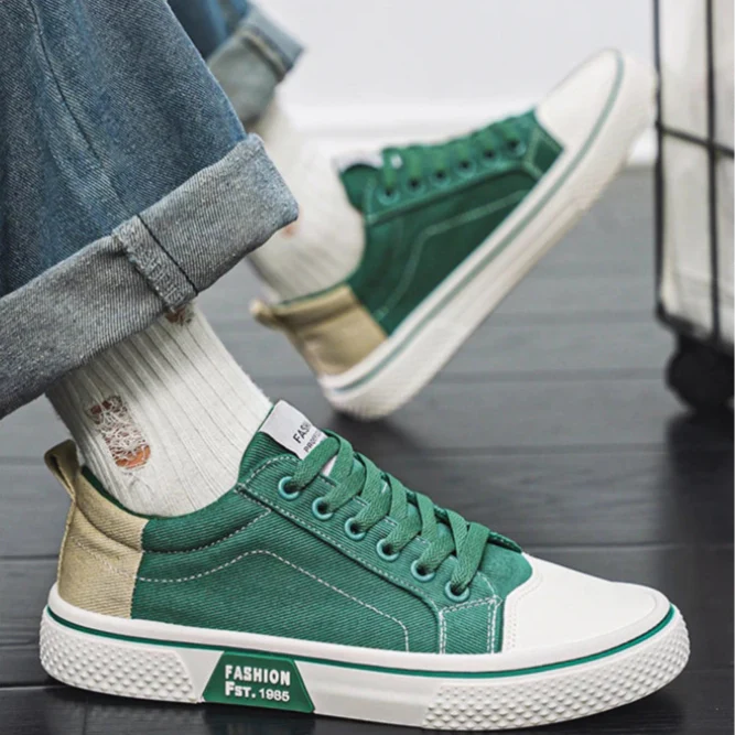 Green canvas sneakers worn with rolled-up jeans, showcasing lace-up front and white sole