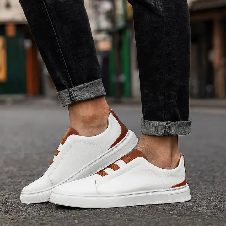 Man wearing white leather slip-on trainers with tan elastic loop laces outdoors