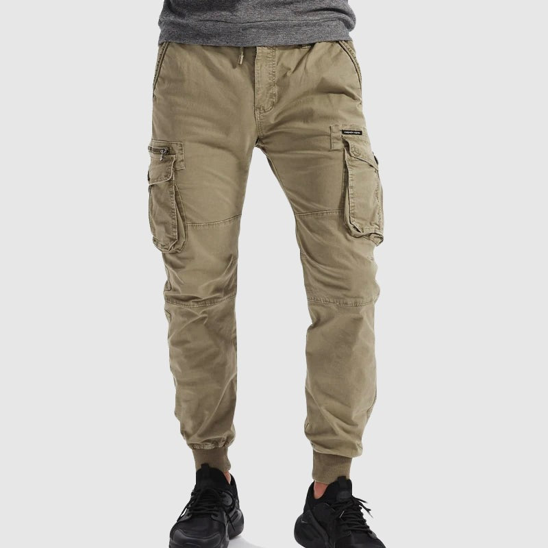Model wearing khaki tactical cargo joggers styled with black trainers