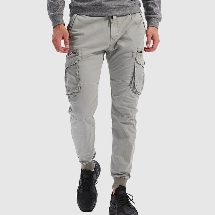Model wearing pale grey tactical cargo joggers with ribbed ankle cuffs