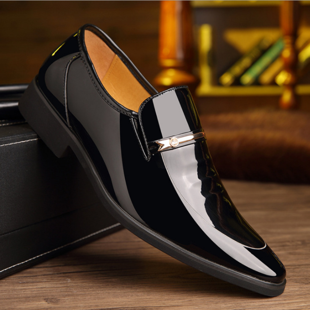 Black patent leather loafer with pointed toe and metal buckle trim