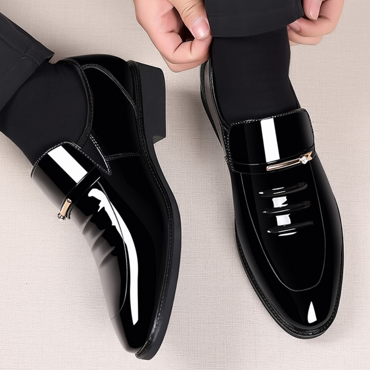Pair of black patent slip-on loafers worn with tailored trousers