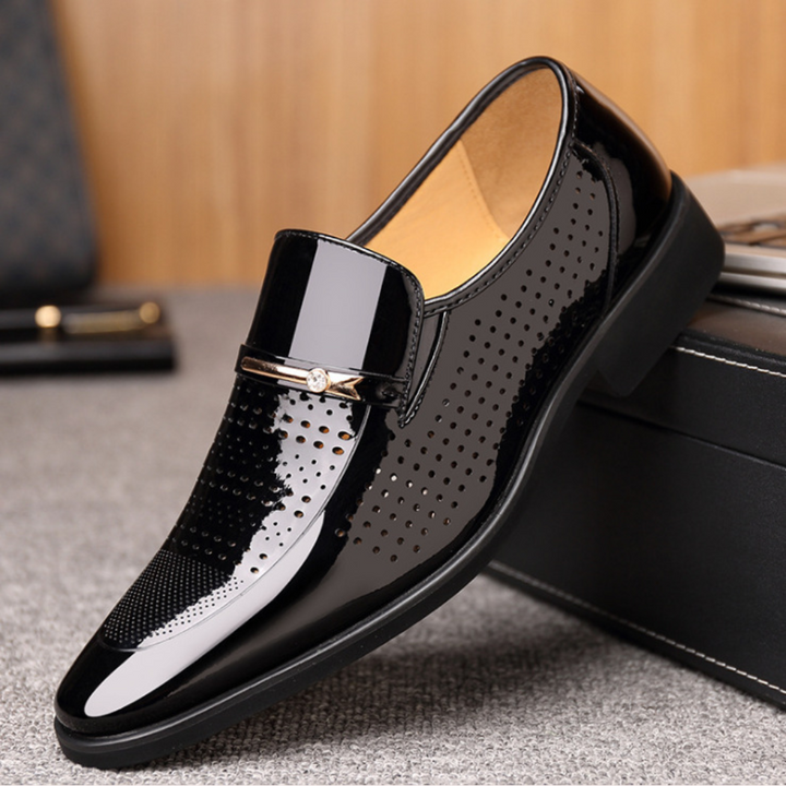Black patent loafer featuring perforated side panel and gold buckle detail