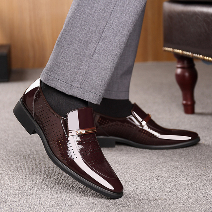 Burgundy patent loafer worn on foot with grey tailored trousers