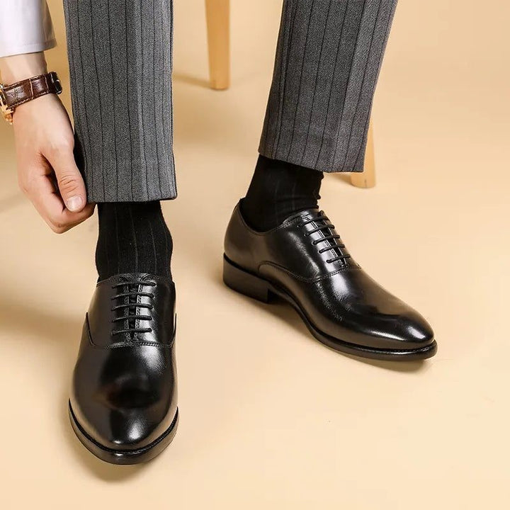 Man wearing black leather lace-up shoes with pointed toe and grey trousers