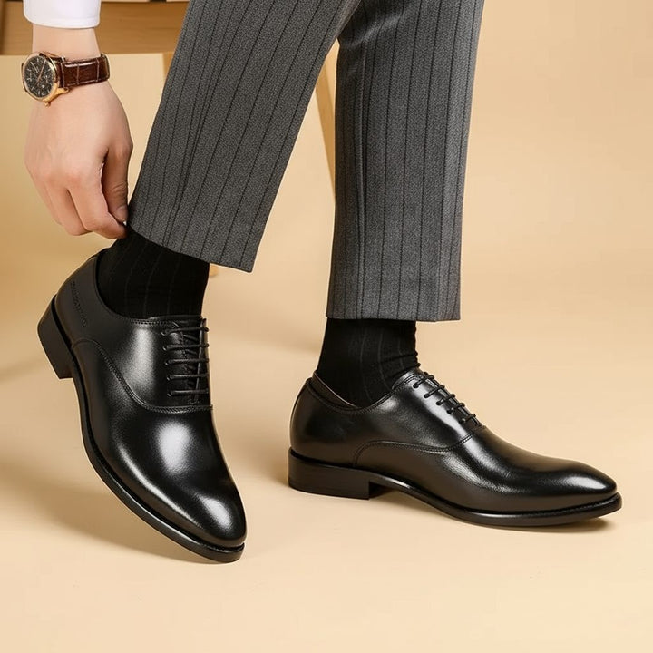 Man tying black leather lace-up shoes with pointed toe and stitched detailing
