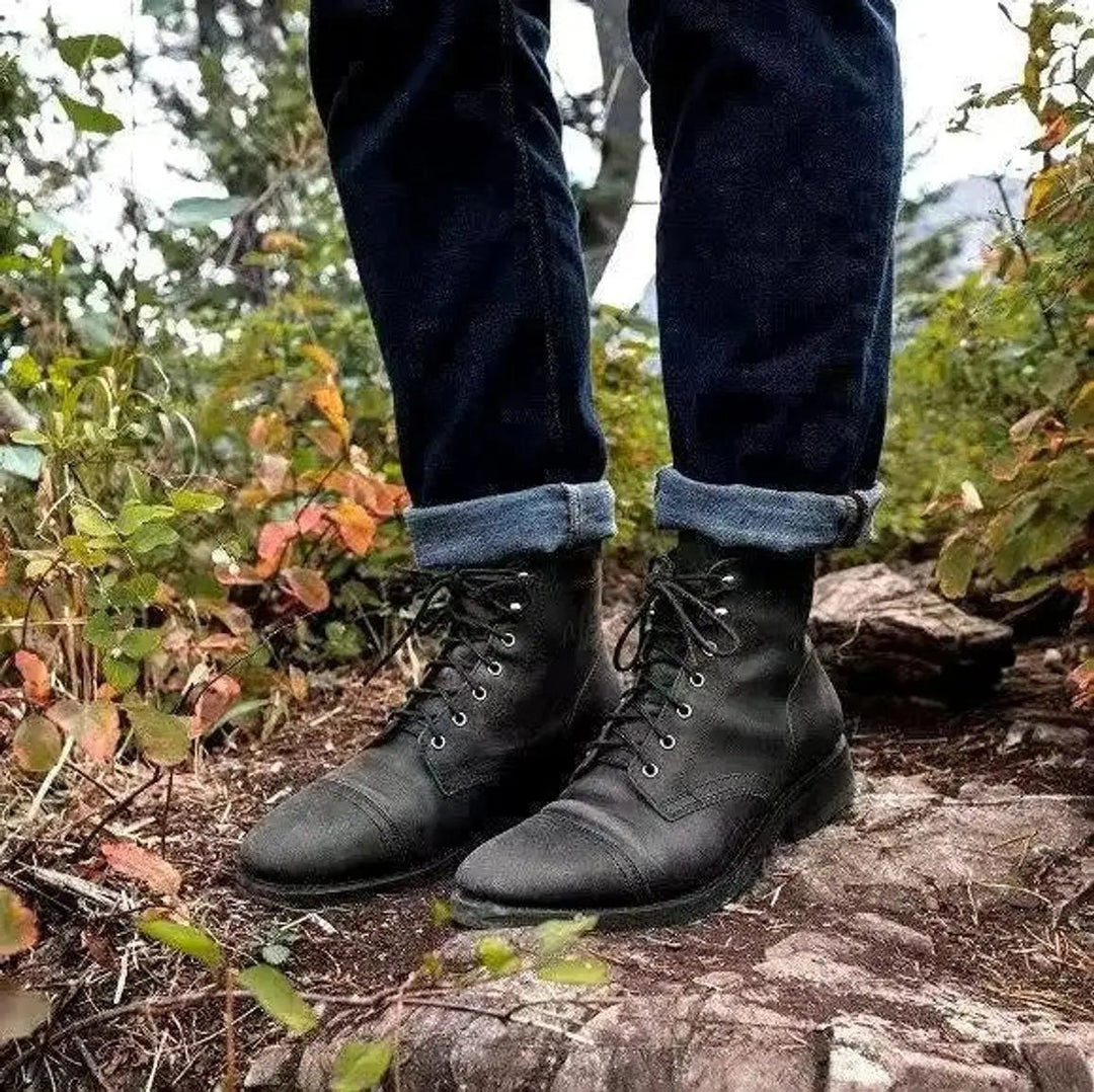 Black leather lace-up ankle boots styled with turned-up dark denim