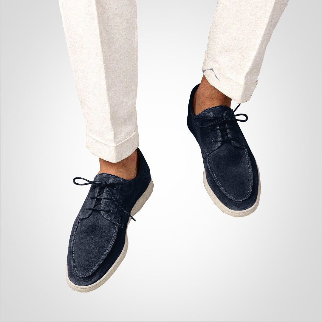 Man wearing navy suede derby loafers with cream trousers rolled at the ankle