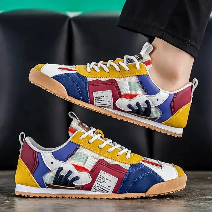 Side profile of mustard and navy multi-panel trainers with gum sole