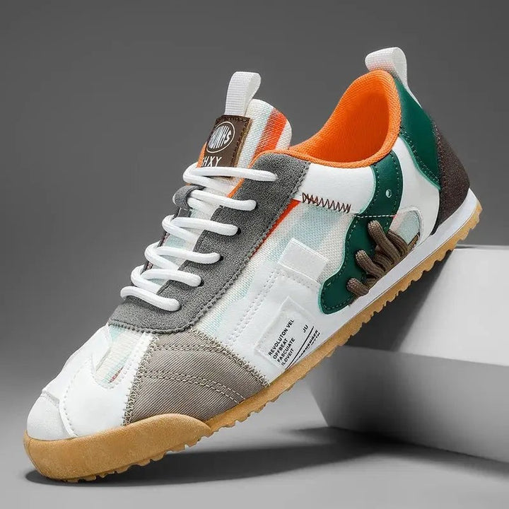White and green multi-panel trainer featuring orange lining and gum outsole