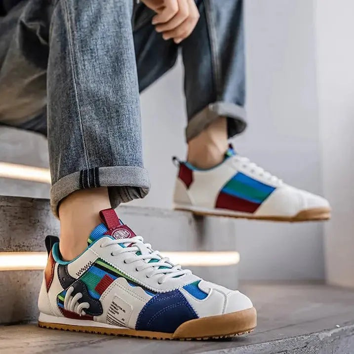 Model wearing striped multi-panel trainers with burgundy accents and gum sole