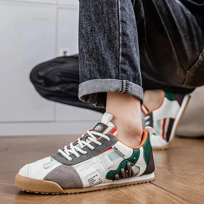 Man wearing green and grey multi-panel trainers with orange trim