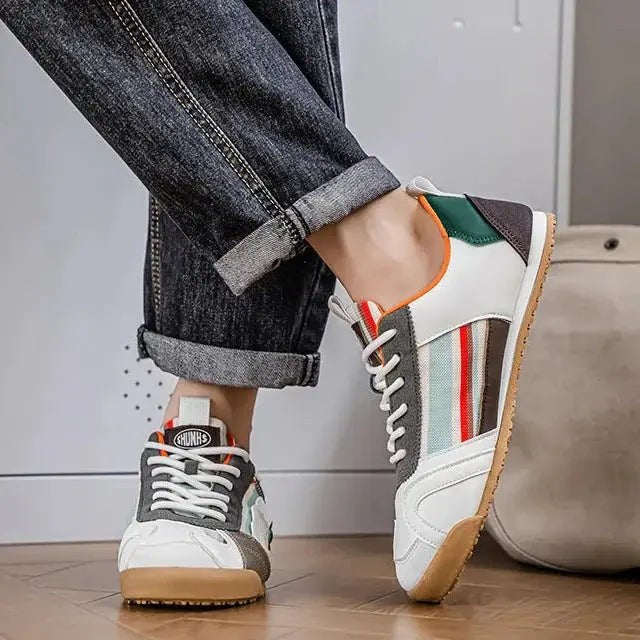 Person wearing striped multi-panel trainers with grey suede overlay