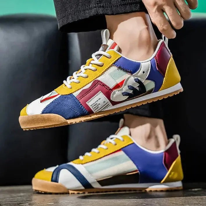 Pair of mustard and navy colour-block trainers held by hand