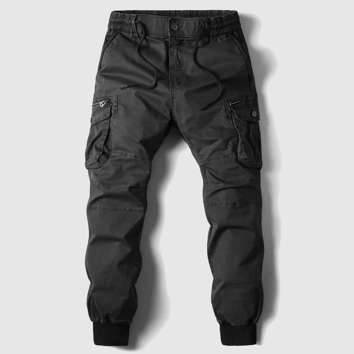 Black cargo jogger trousers laid flat, showcasing multiple pockets and elastic cuffed hem