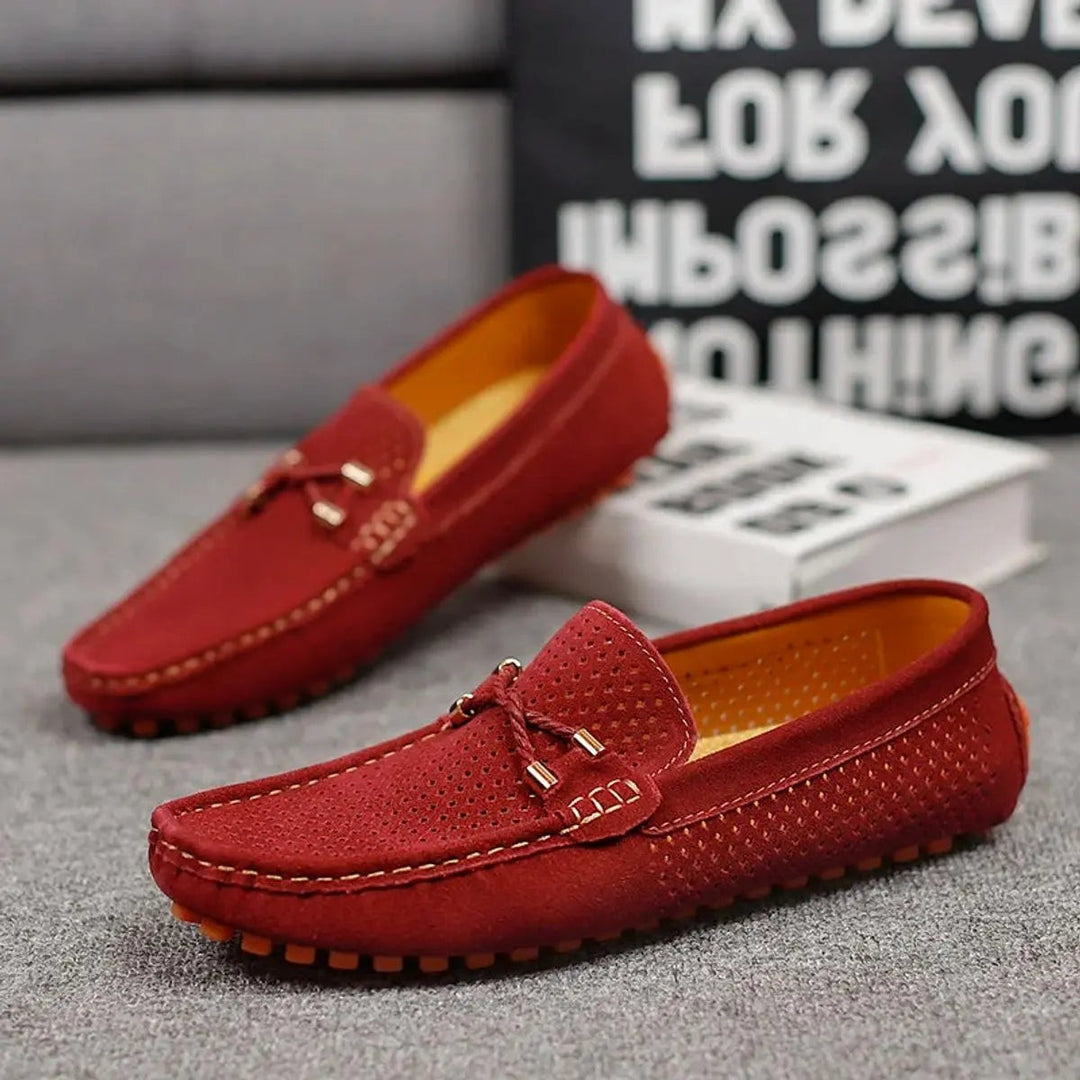 Burgundy suede driving loafers paired together against grey backdrop