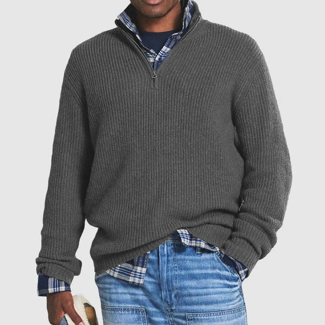 Grey ribbed quarter-zip jumper worn over layered plaid shirt and jeans