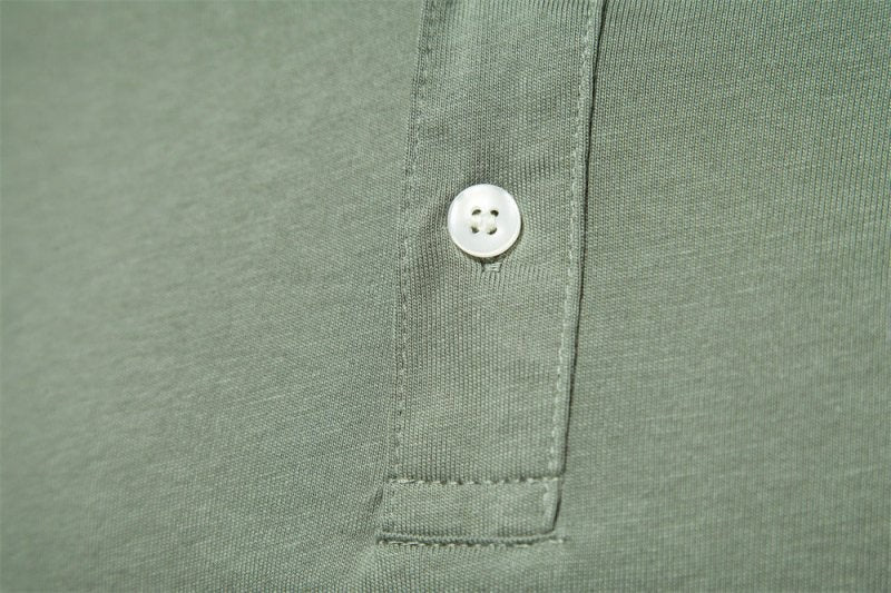 Close-up of mother-of-pearl button on olive green polo placket