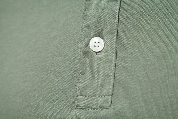 Close-up of mother-of-pearl button on olive green polo placket