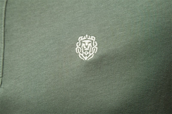 Close-up of embroidered lion crest logo on olive green polo