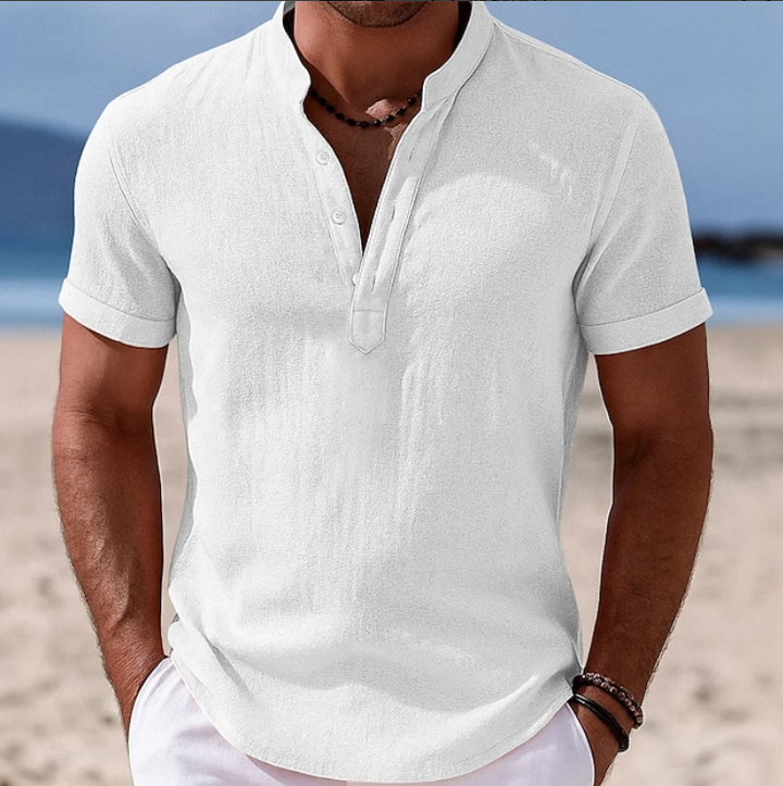 White linen-blend shirt with grandad collar and rolled sleeves, beach backdrop