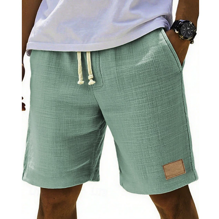 Sage green linen-blend shorts with drawstring waistband and tan patch