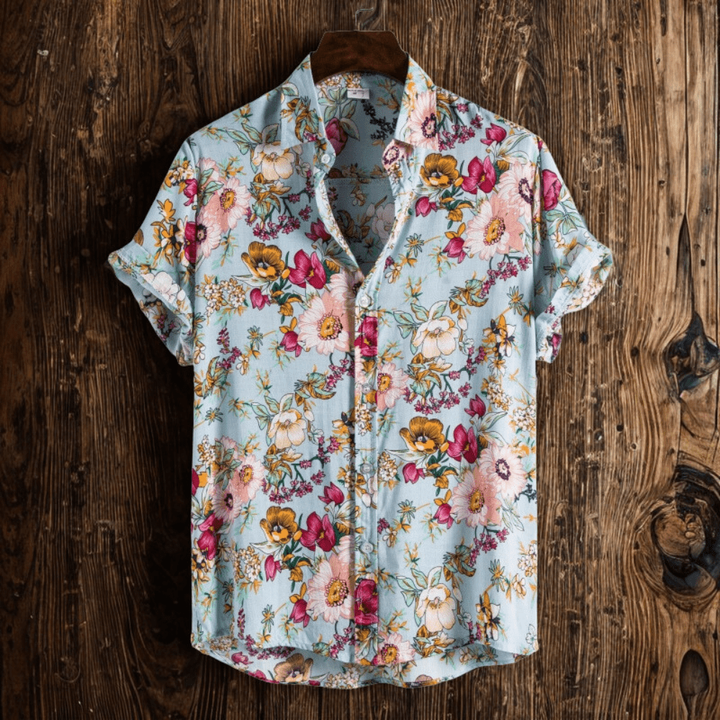 Men's short-sleeve floral shirt in pale blue with button-down front, hung against wood