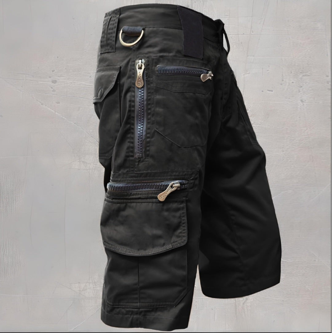 Black cargo shorts with multiple zip pockets and D-ring detail, side view