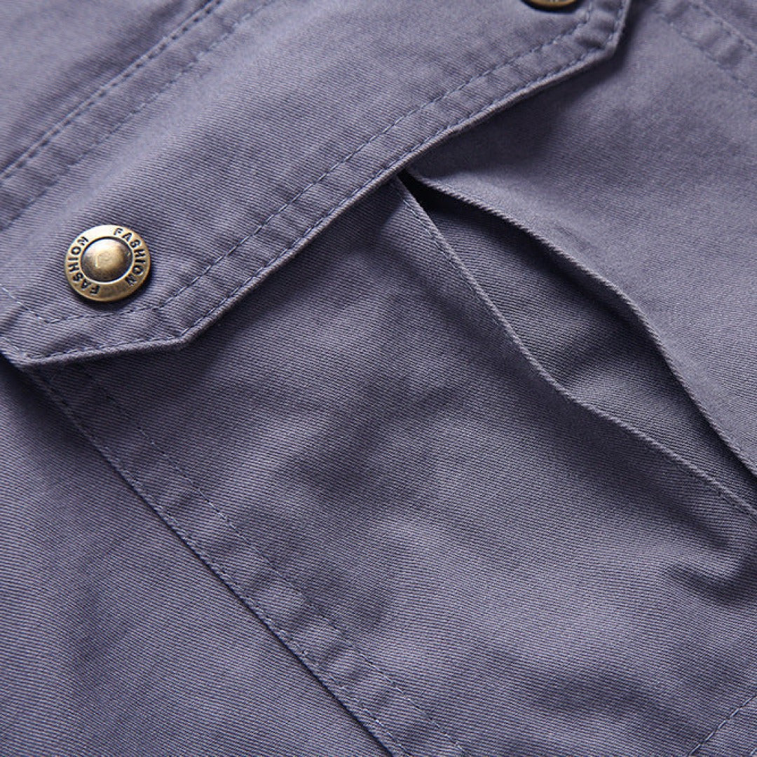 Detailed view of grey cargo shorts' flap pocket with branded snap button