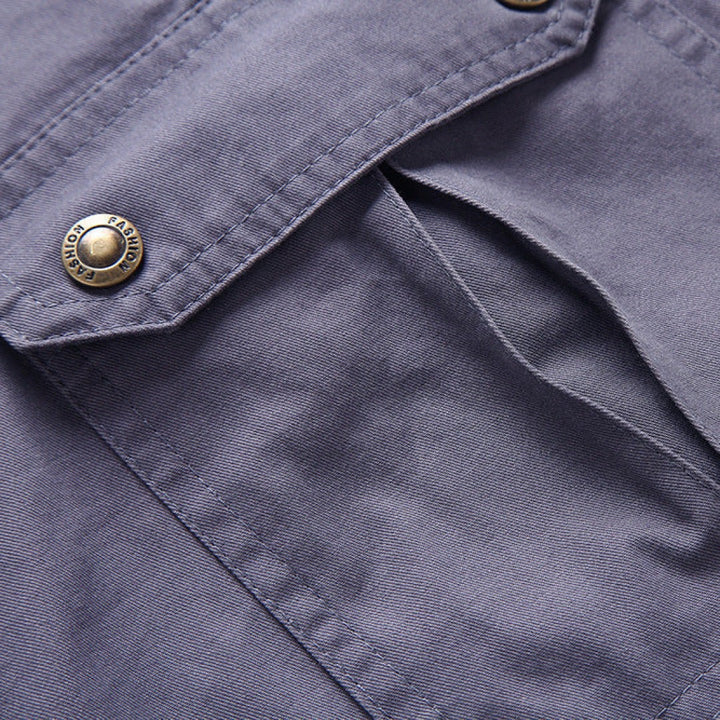 Detailed view of grey cargo shorts' flap pocket with branded snap button