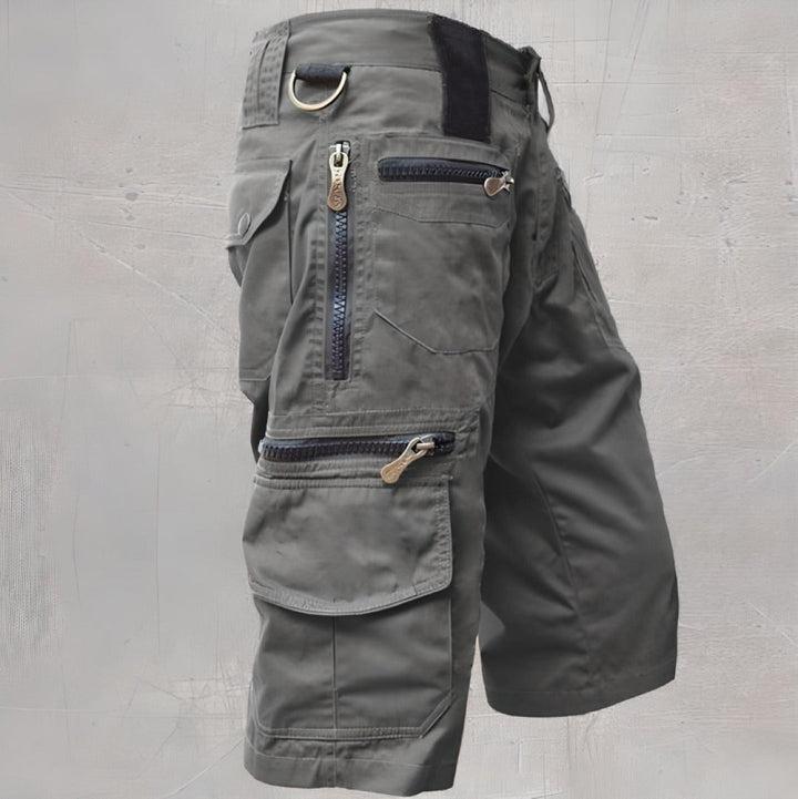 Grey cargo shorts featuring zip pockets and adjustable waist tab, side profile