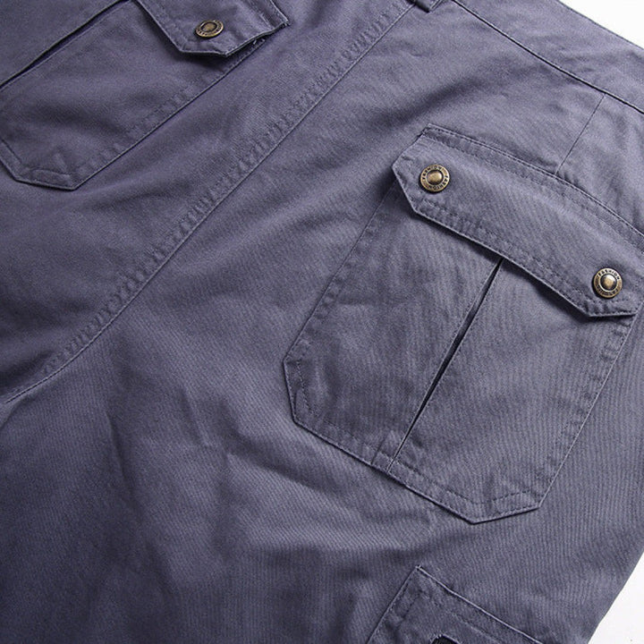 Grey cargo shorts detail showing press-stud flap pocket with brass button