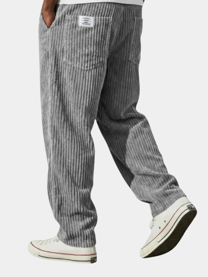 Grey corduroy trousers with wide-rib texture styled with white trainers