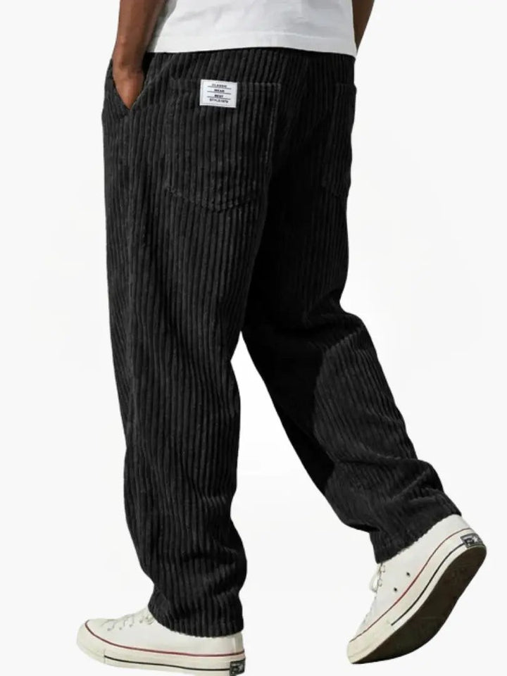 Black corduroy trousers with bold ribbing and loose, casual fit