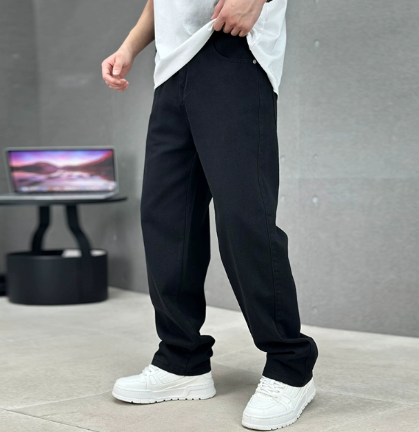 Black loose fit straight leg trousers paired with white trainers