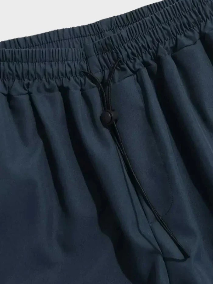 Close-up of navy cargo trousers' elasticated waistband with adjustable toggle drawstring