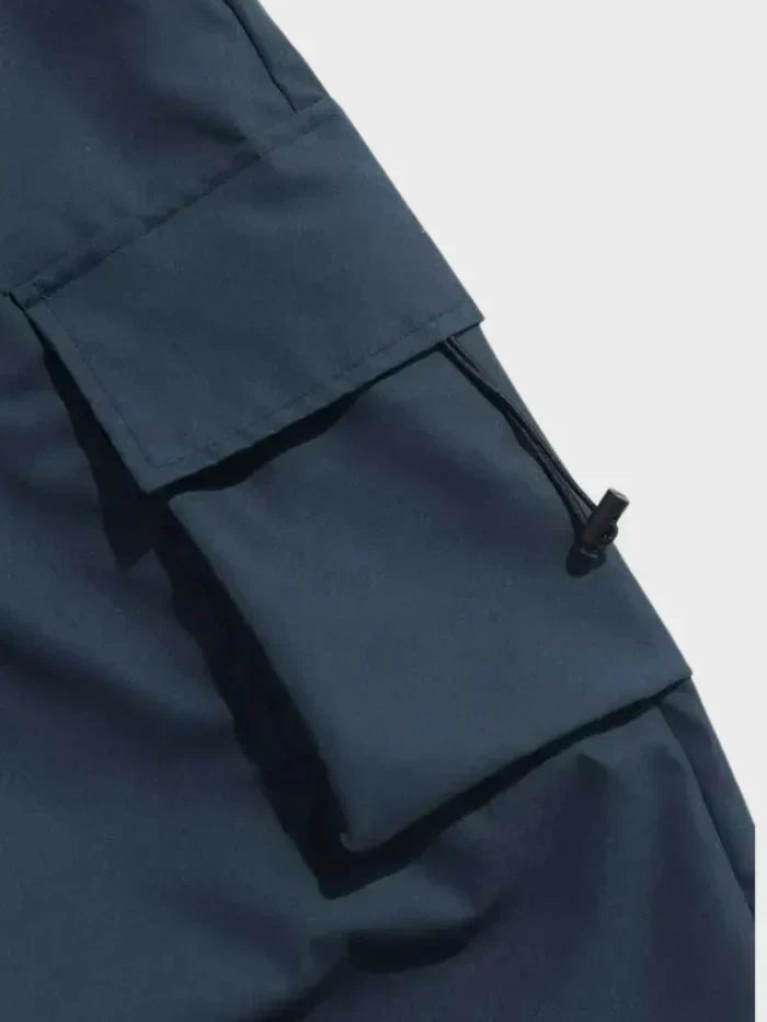 Close-up of navy cargo trousers' flap pocket with adjustable toggle fastening