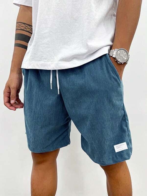 Man modelling teal corduroy shorts with white drawstring waist and label detail