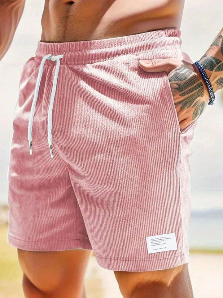 Dusty pink corduroy shorts with white drawstring cords, close-up side view