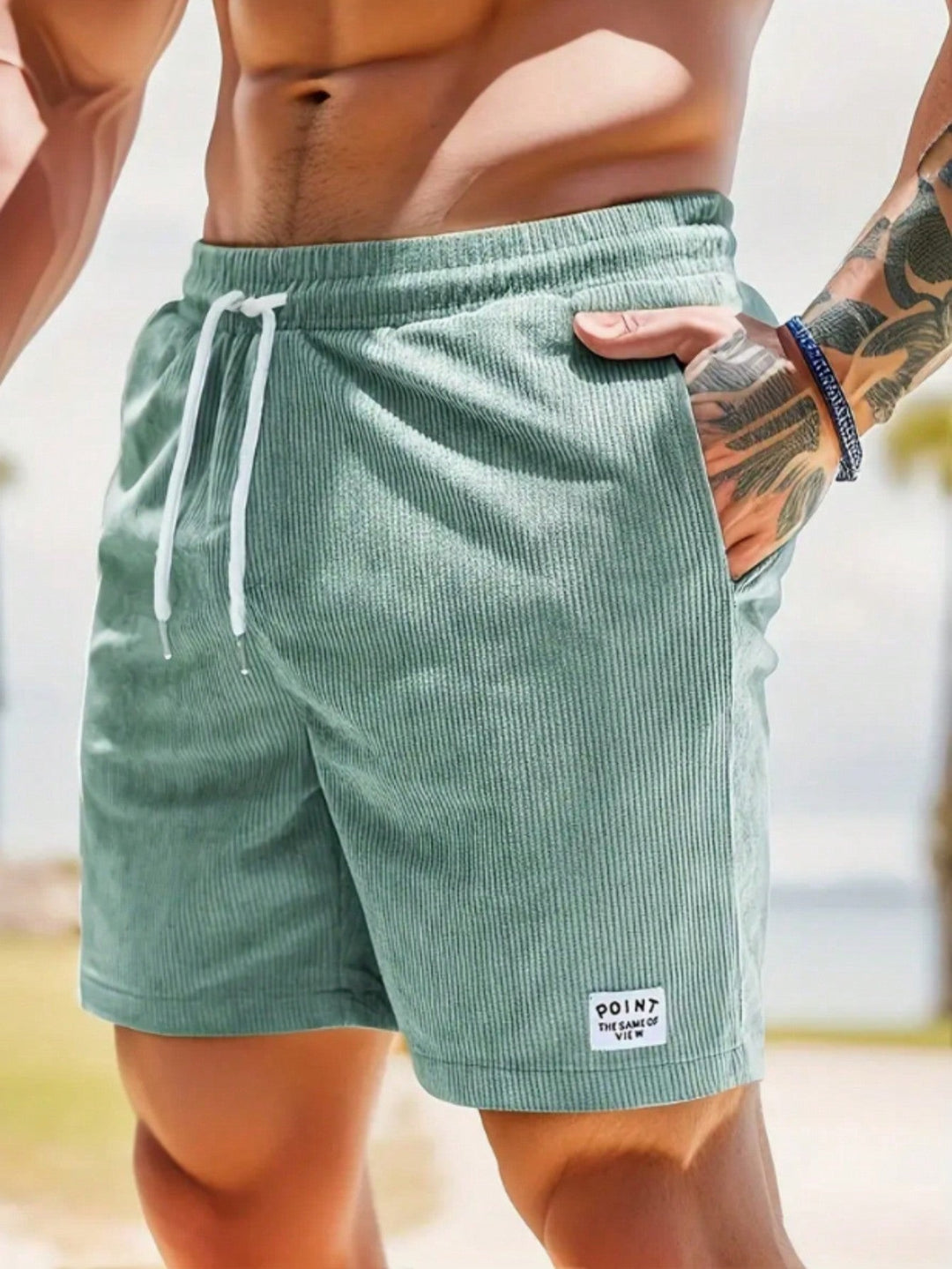 Sage green corduroy shorts with drawstring waist, worn at seaside location